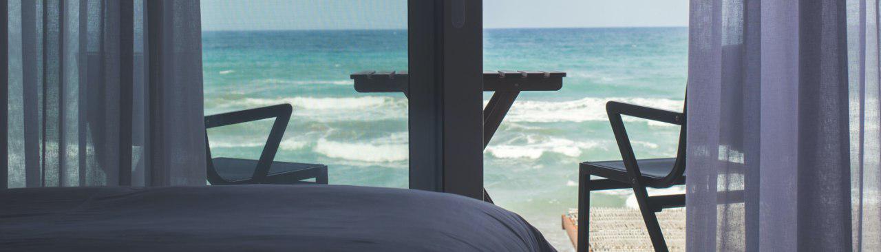 cama y ventana de hotel de playa 1500x430